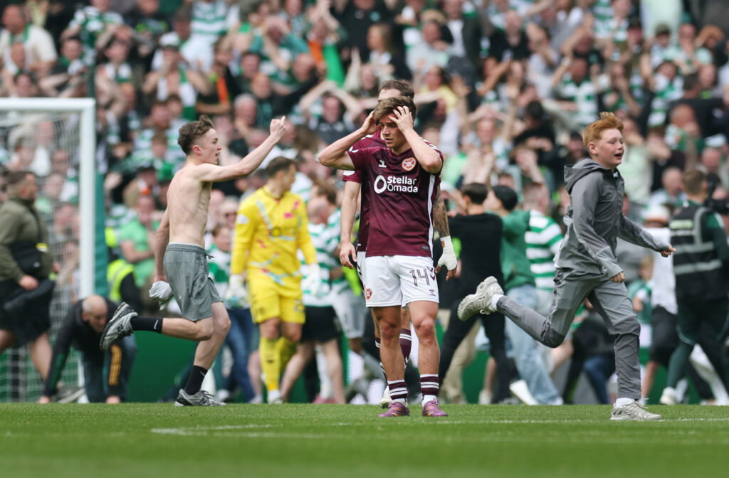 Heart of Midlothian players are seen at full time as Celtic fans invade the pitch