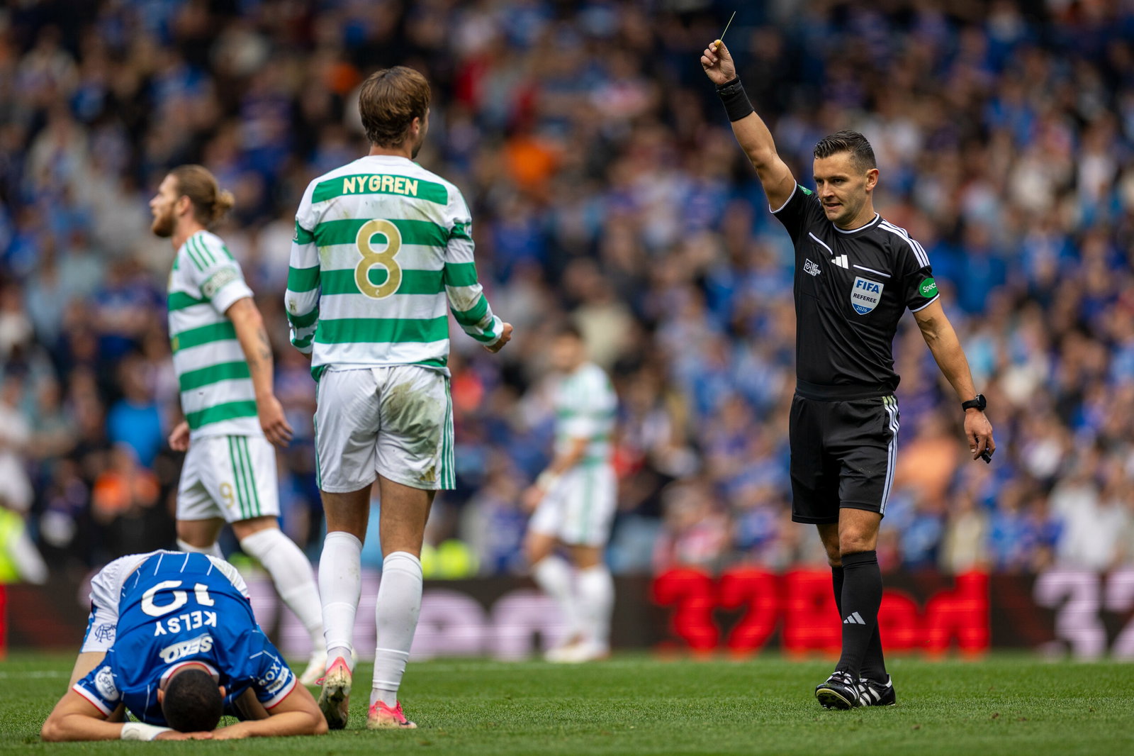 Benjamin Nygren of Celtic is yellow carded by referee Nick Walsh.